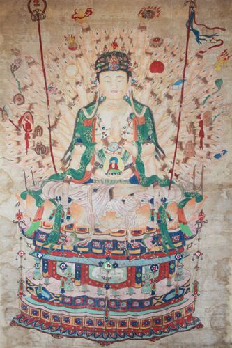 《千手千眼观音》 明 绢本 纵170厘米 横92厘米 菩萨分别持双胜、如意、莲枝、禅杖、经文等。头顶髻珠螺发，面容清秀端庄，面部、手足渲染精致，有立体感，衣纹有工细描金。座下莲台及须弥宝座十分精美。