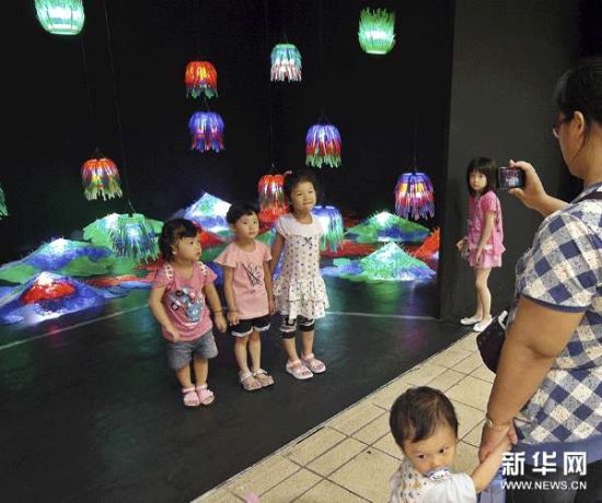 小参观者在由废旧物品制作的展品前拍照。