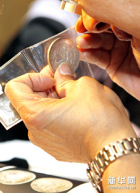 6月27日，一位买家在鉴别一枚民国时期的银币。新华网图片 张明 摄