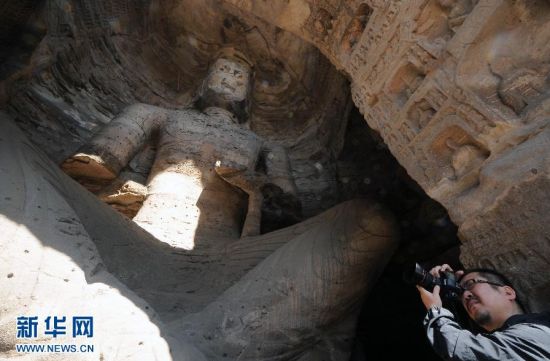 一位游客正在拍摄弥勒三尊洞内的造像（9月29日摄）。 新华社记者 范敏达 摄