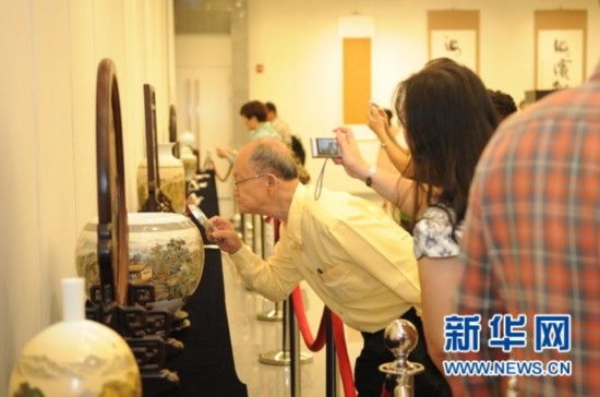 　7月26日，“古韵焕采”陶瓷微书精品展在曼谷拉开帷幕。图为一名参观者手持放大镜仔细观看瓷器上的文字。（新华社记者 毕尚宏 摄）